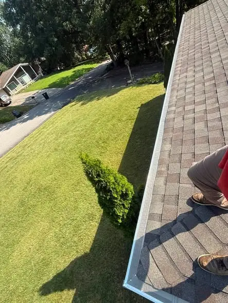 Crew hanging a white seamless aluminum gutter along a Chattanooga roofline